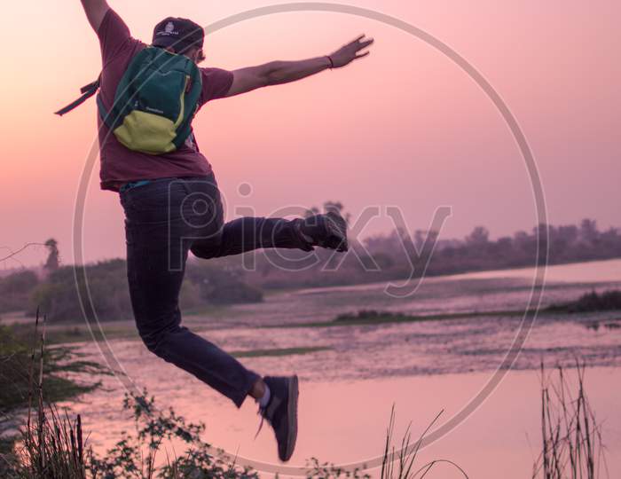 A boy jumping near a lake