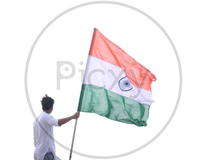 Cheerful young Indian man standing and holding national flag for motivation on top of roof during lock down