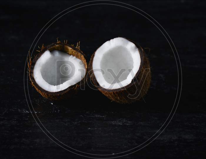 Coconut with half on a dark background. Organic healthy food concept.