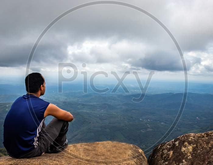 Man Isolated Sitting On The Hilltop Watching Landscape