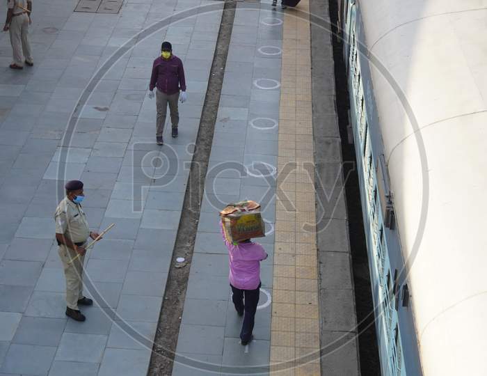 Indian migrant workers affected due to COVID 19 Corona Virus nationwide lockdown. Migrant workers returning back home via special trains or bus. Indian Police on duty. Standing in queue on railway station with Social distancing and wearing medical mask.