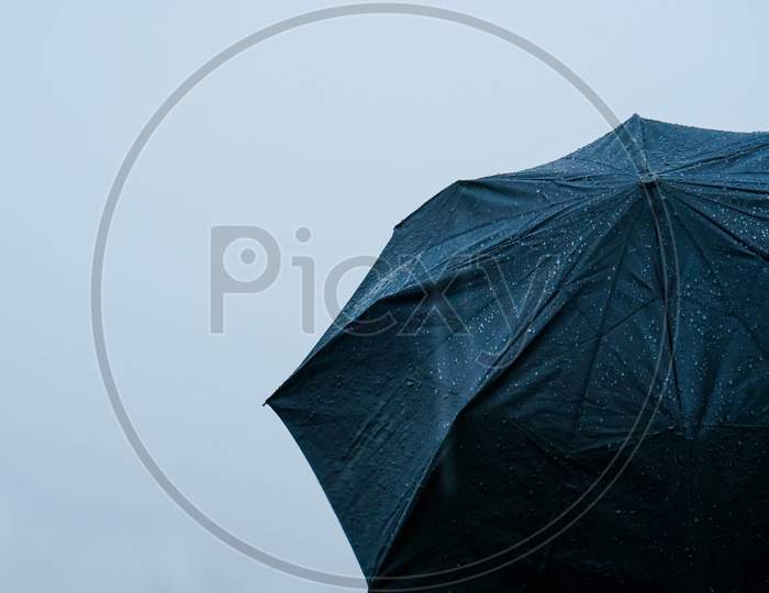 Alone man standing out in rain with an umbrella