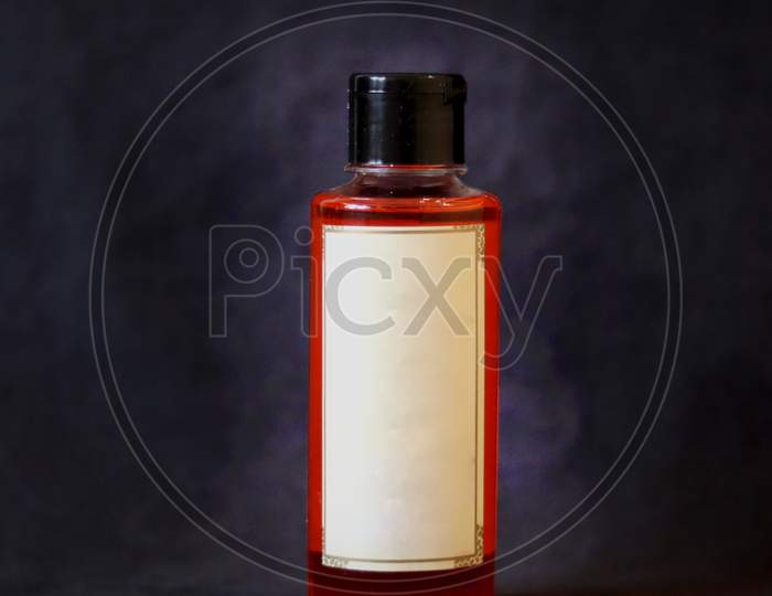 Orange Oil Bottle With Off White Label And Black Bottle Cap On Dark Grey Textured Background.