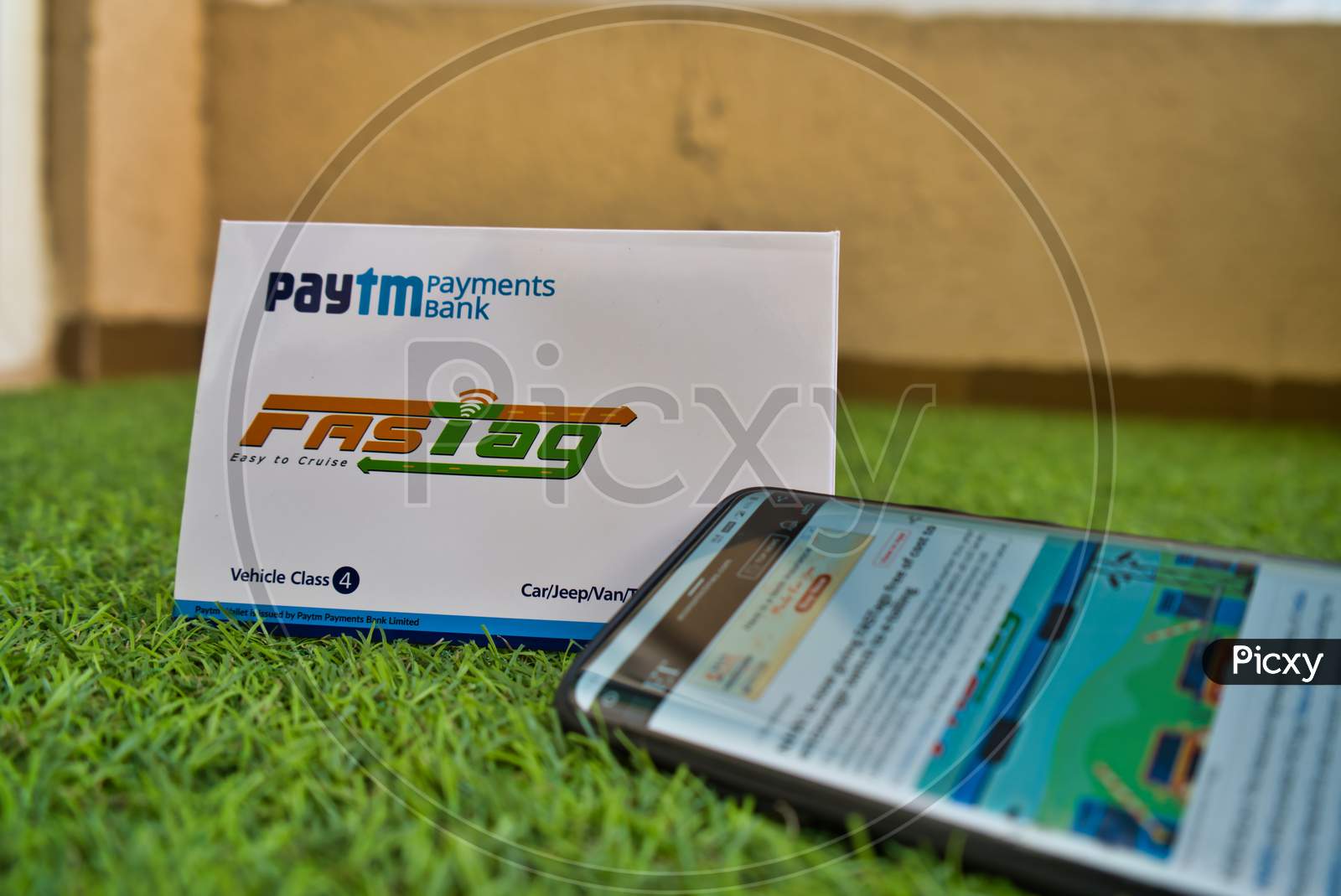Fast Tag Provided By Paytm Payment Bank On Green Grass With A Mobile Phone Logged Into Fast Tag Website.