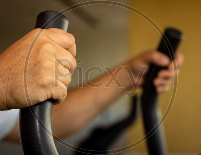 Adult Man Doing Exercise In The Gym. In Machine Doing Aerobic Exercise.