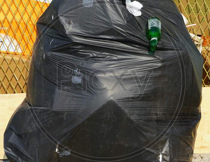 Dubai Uae December 2019 - Solo Overflowing Bag Of Black Garbage Trash Bag Kept Outside. Mcdonalds And Bottle Coming Out Of Torn Black Trash Bag. Big City, Pollution Trash.