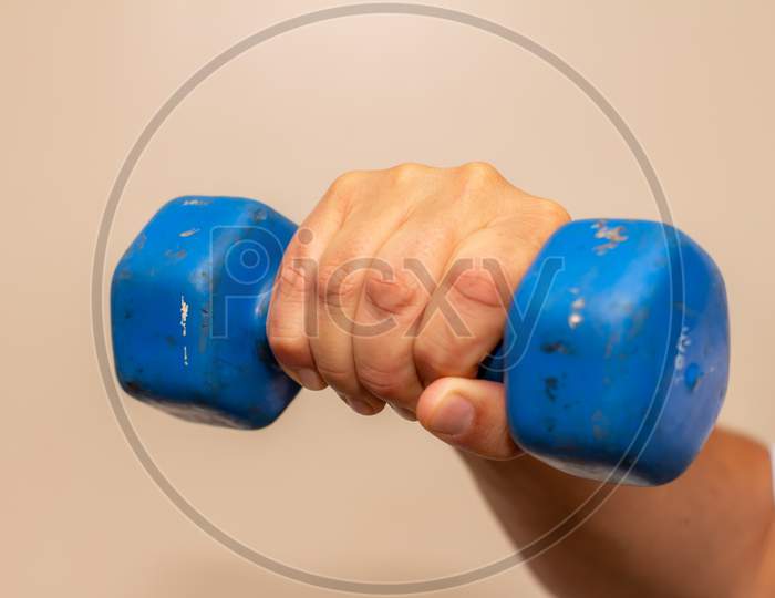 Man Exercising His Arm With A Small Blue Dumbbell. Muscle Exercise