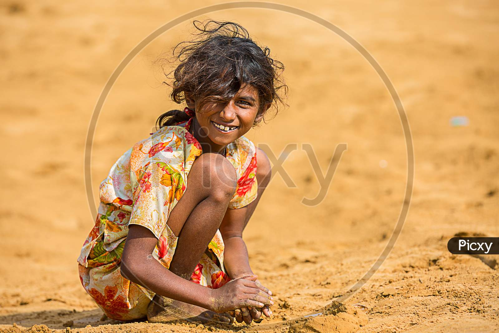 Jodhpur, Rajasthan, India - June 18Th, 2019: Poor Rural Girl Playing With Sand In Hot Summer, Smiling Towards Camera, Poverty Unprivileged Indian Children.