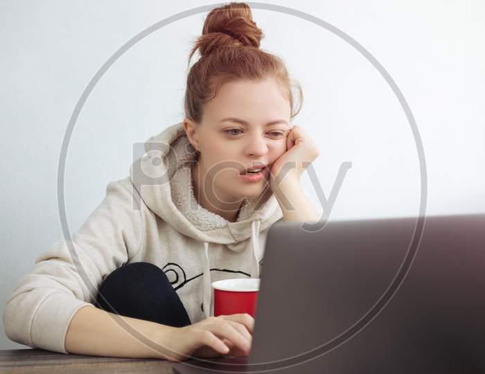 Young Caucasian woman looking bored in front of laptop at home. Work from home concept