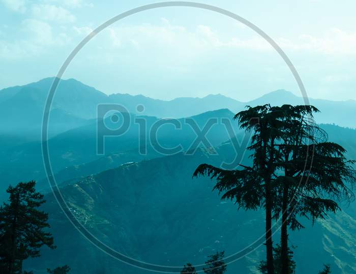 Landscape With Silhouettes Of Mountains With Mist And Cold Sunlight