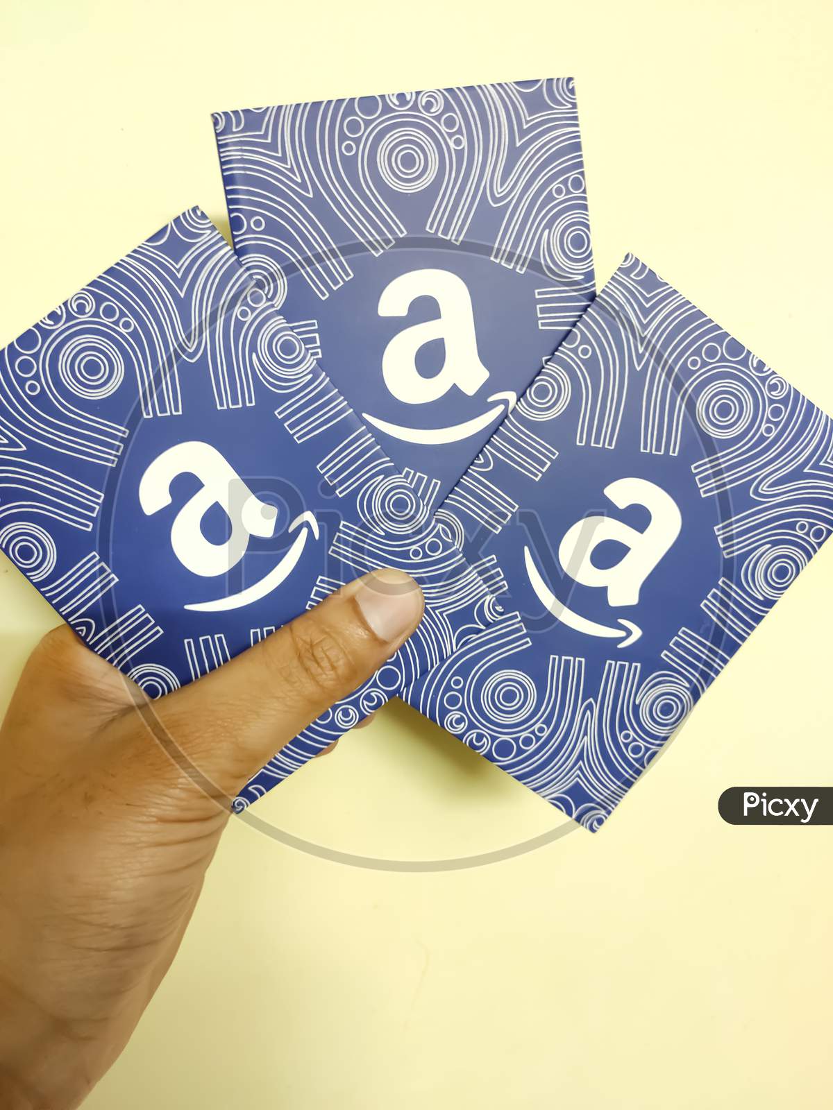 A hand holds a Amazon gift card, which allows the recipient to purchase items from the Amazon.com website