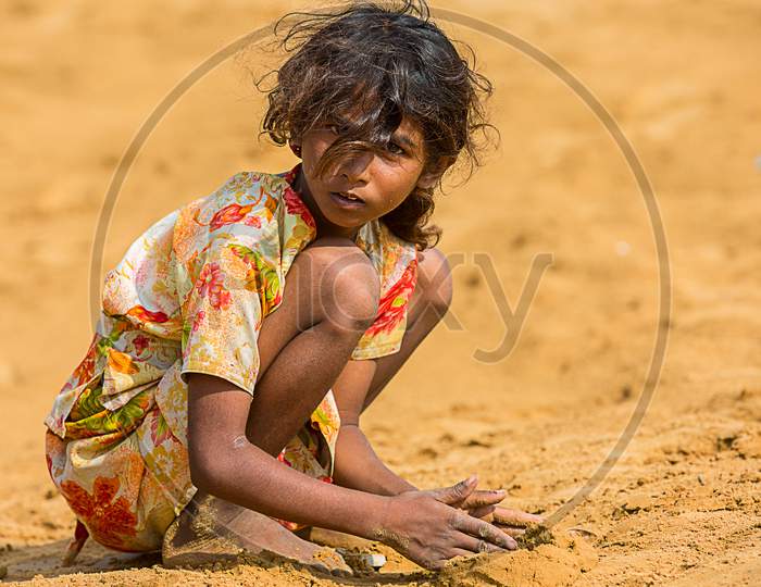 Jodhpur, Rajasthan, India - June 18Th, 2019: Poor Rural Girl Playing With Sand In Hot Summer, Poverty Unprivileged Indian Children.