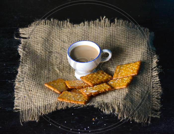 A cup of tea with biscuits on old wooden dark background