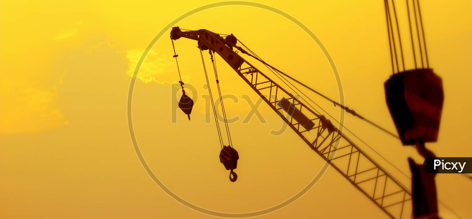 Silhouette Construction Crane On Sunset Sky.Blurry Background Of Crane At Sun Set.Selective Focus.