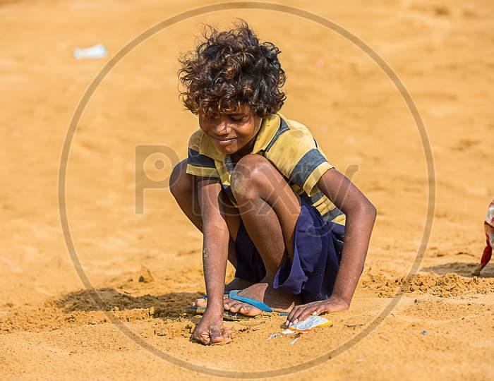 Jodhpur, Rajasthan, India - June 18Th, 2019: Poor Rural Boy Kid Playing With Sand In Hot Summer, Smiling Towards Camera, Poverty Unprivileged Indian Children.