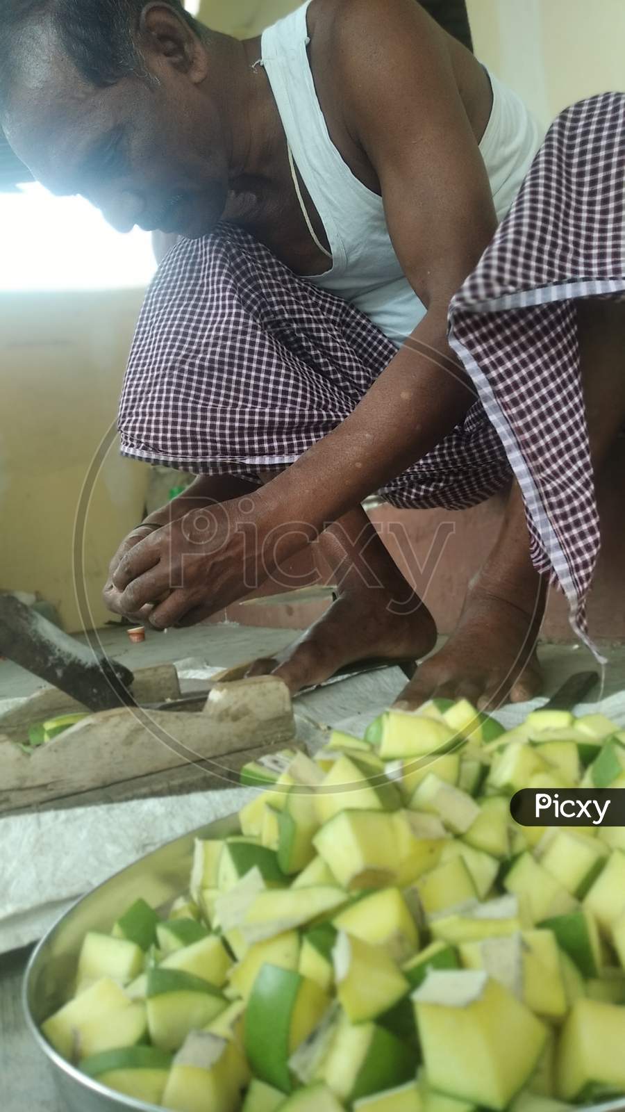 Focused view An Indian Father cutting mangoes for making Indian traditional mango pickle