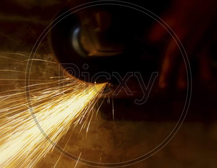 Electric Wheel Grinding On Steel Structure In Factory. Sparks From The Grinding Wheel.Selective Focus With Blurry Background.