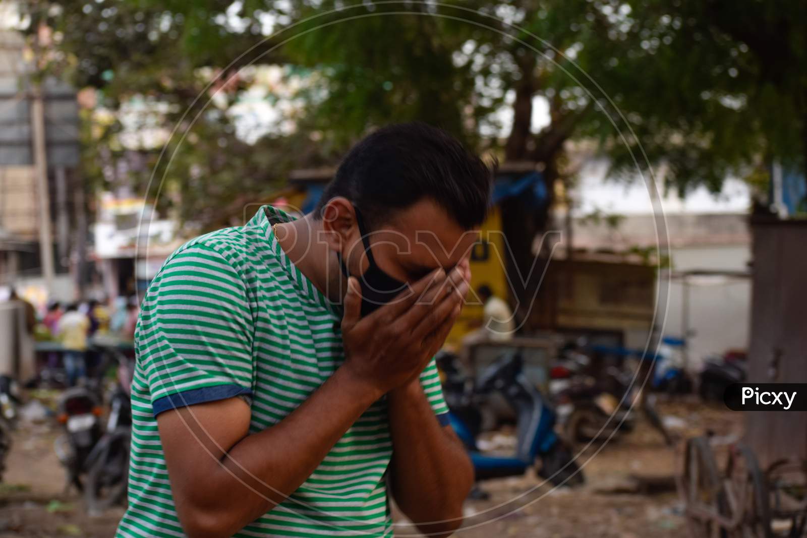 Bharuch, Gujarat/India - March 20, 2020: An Indian men feeling sick, coughing, wearing protective mask against transmissible infectious diseases and as protection against Covid-19 Corona virus.