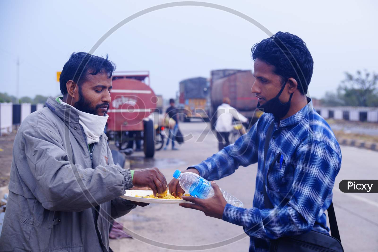 Two migrants sharing a plate of food while traveling to their native place in lockdown