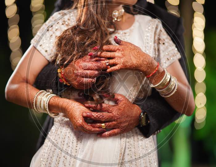 Photo of the couple posing and holding each other's fingers and showing rings during the typical Indian engagement ceremony.