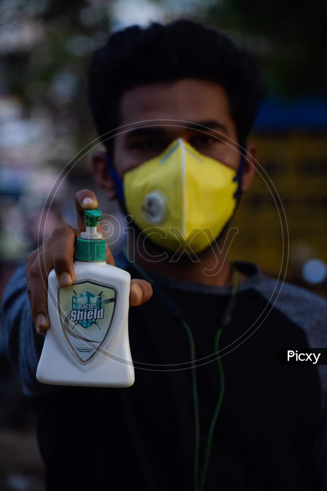 Bharuch, Gujarat/India - March 20, 2020: A men wearing CORONA VIRUS MEDICAL MASK for the prevention of COVID-19 CORONA VIRUS while showing sanitizer in his hand. Selective focus.