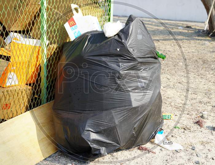 Dubai Uae December 2019 - Solo Overflowing Bag Of Black Garbage Trash Bag Kept Outside. Mcdonalds And Bottle Coming Out Of Torn Black Trash Bag. Big City, Pollution Trash.