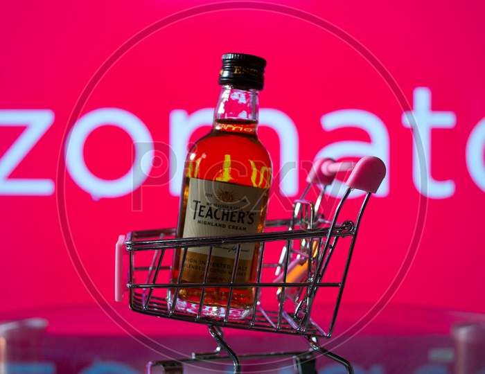 A bottle of whiskey in a trolley in front of a zomato board