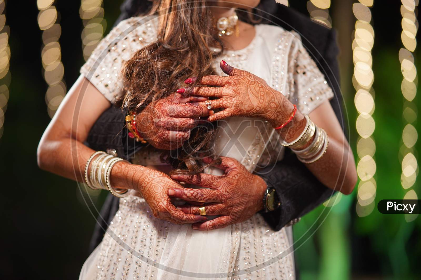 Photo of the couple posing and holding each other's fingers and showing rings during the typical Indian engagement ceremony.