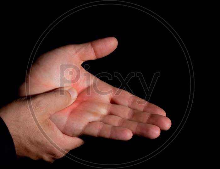 Man'S Hands With Pain In The Palm Of The Hand. Massage In The Palm With The Thumb. Hands Of Young White Man, On Black Background.