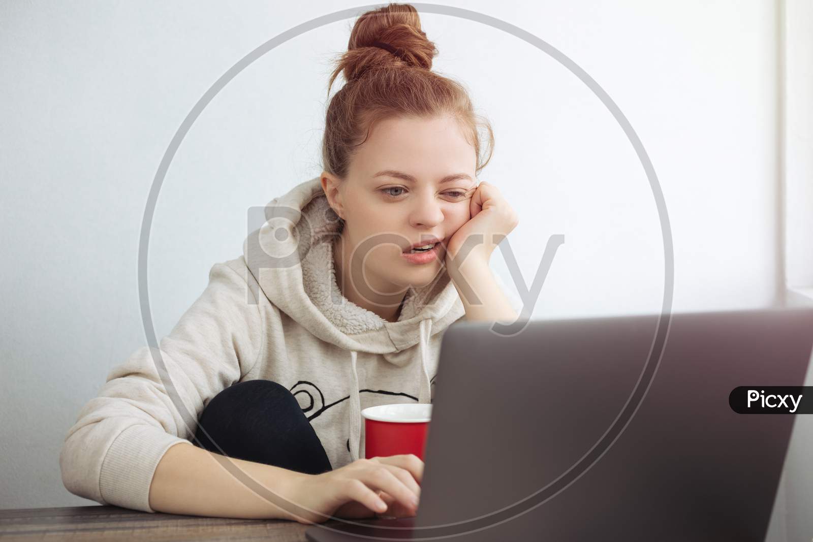 Young Caucasian woman looking bored in front of laptop at home. Work from home concept
