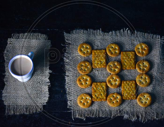 A cup of tea with biscuits on old wooden dark background