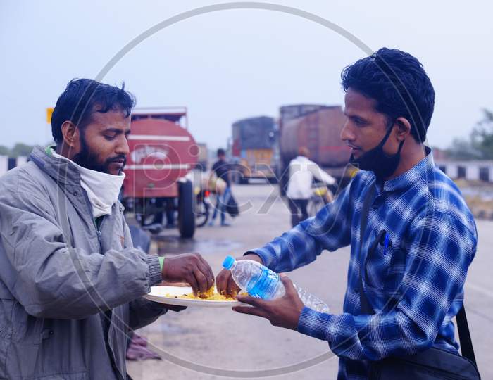 Two migrants sharing a plate of food while traveling to their native place in lockdown