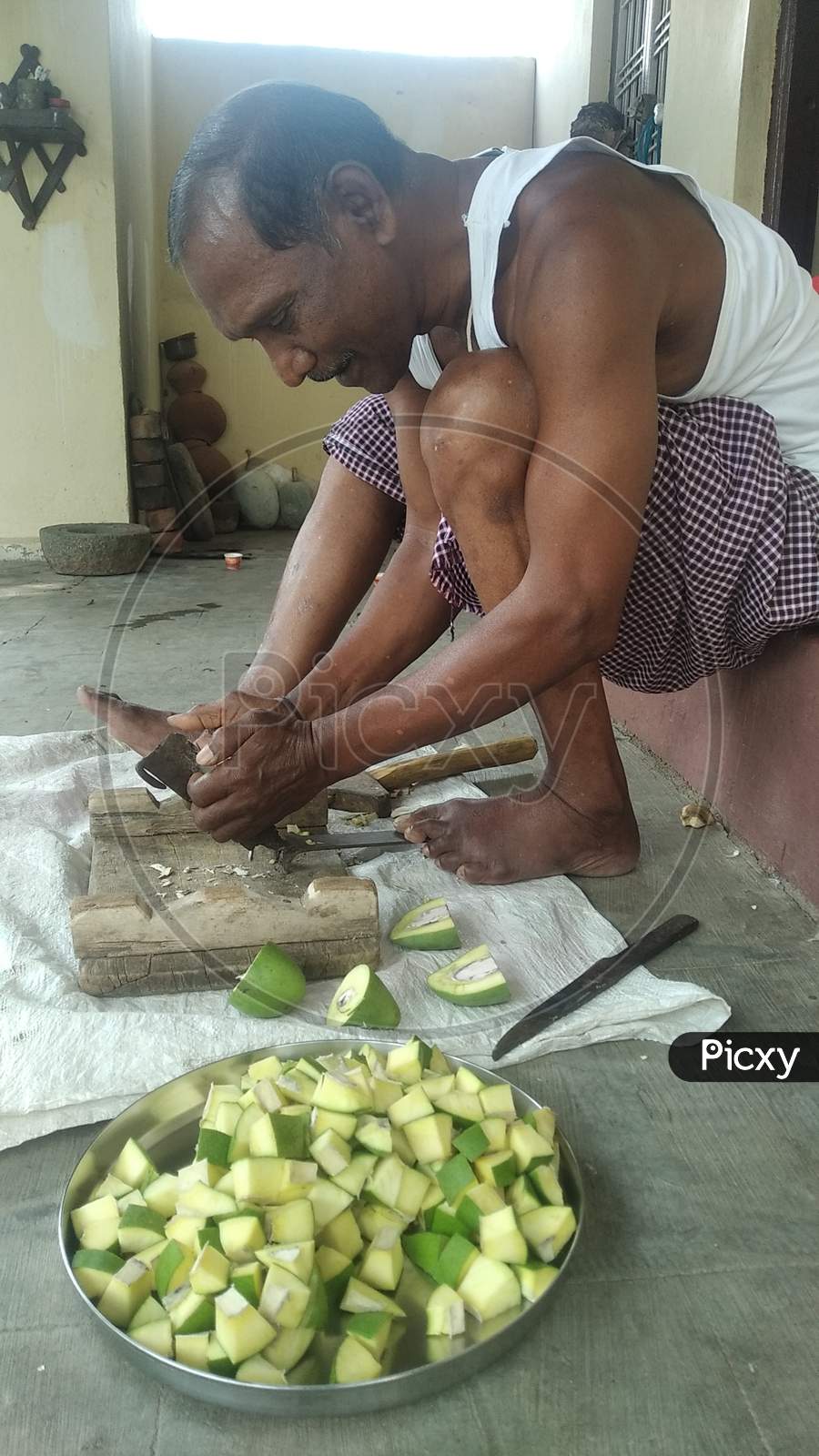 An Indian citizen cutting mangoes for making mango pickle