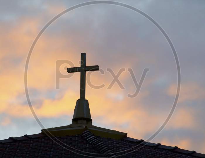Silhouette Of A Religious Cross Against Sunset Sky