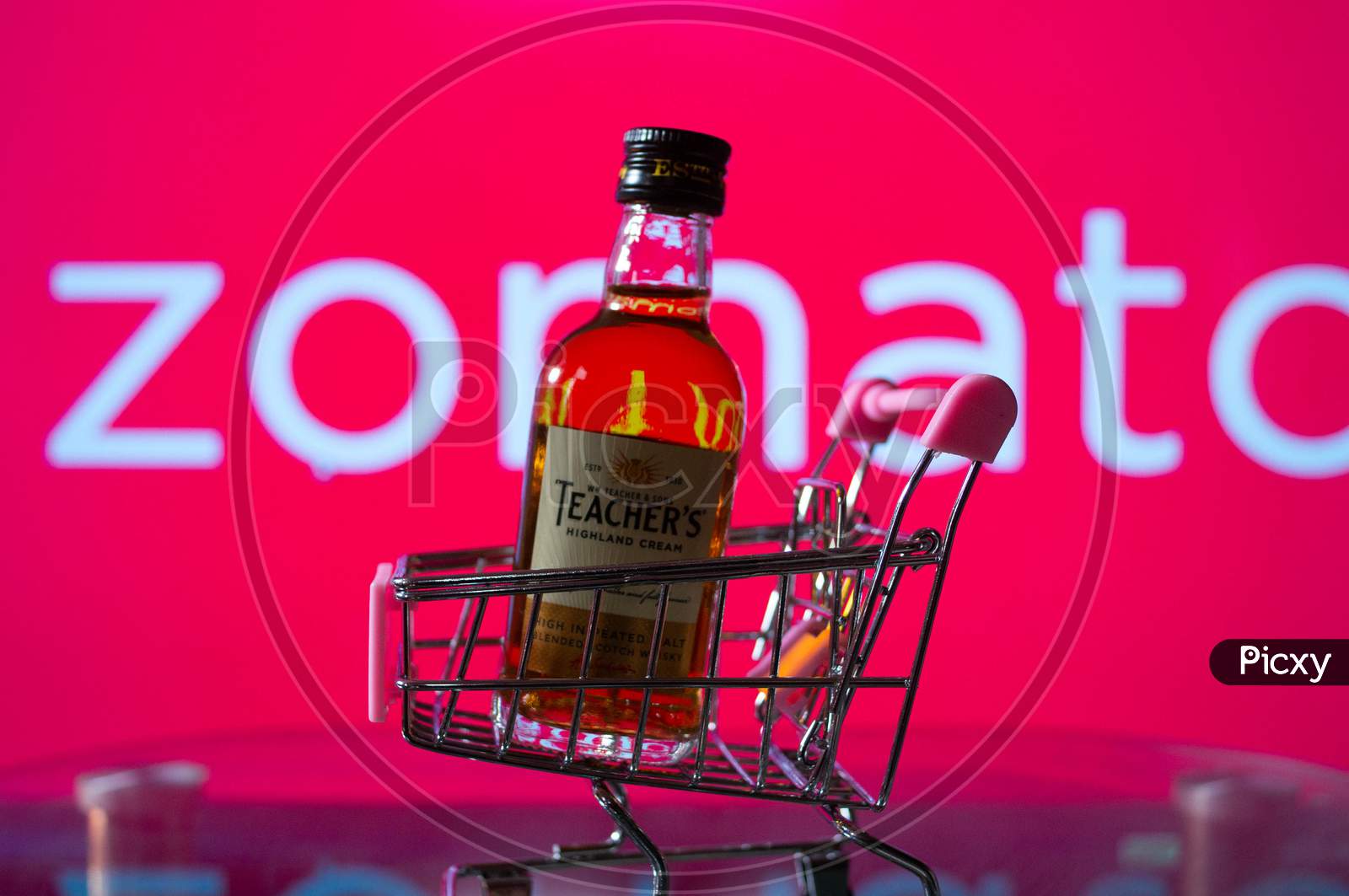 A bottle of whiskey in a trolley in front of a zomato board