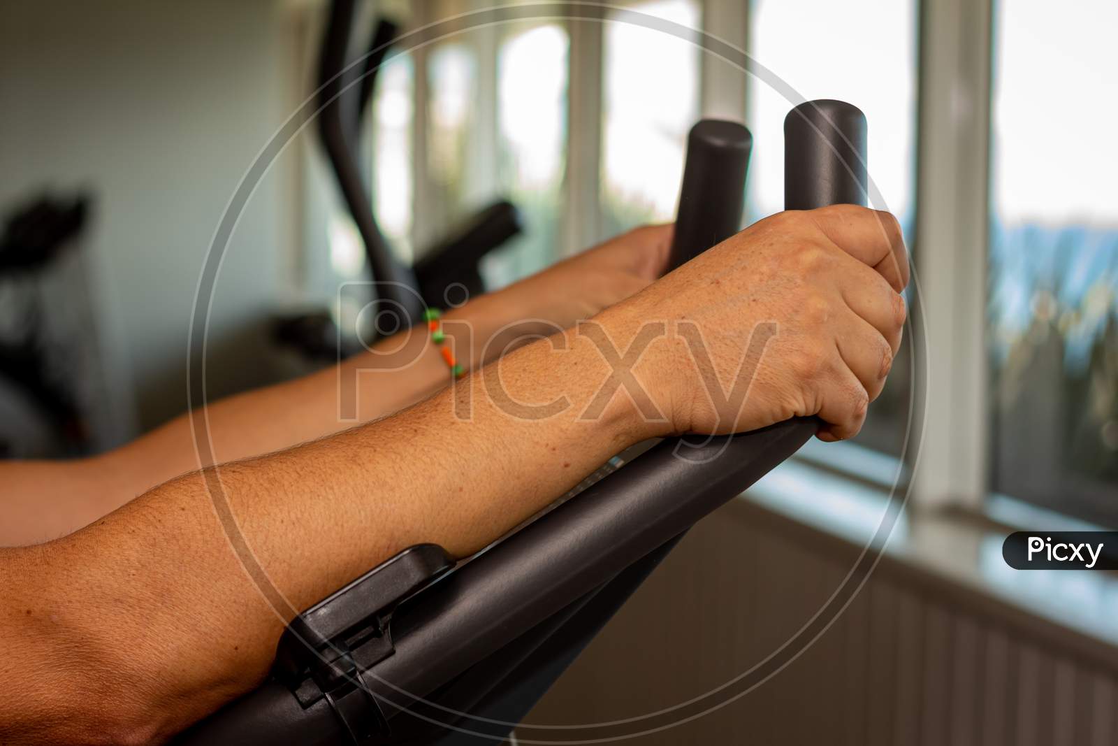 Adult Man Doing Exercise In The Gym. In Machine Doing Aerobic Exercise.