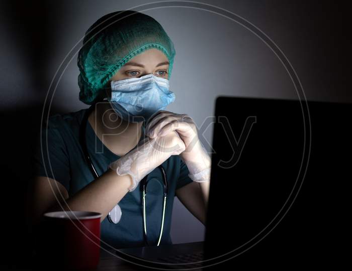 Caucasian woman doctor nurse in surgical mask looks tired, exhausted at night because of covid