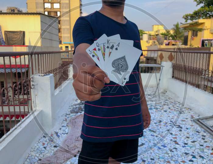 Young Indian Man Holding Poker or Playing Cards With Blur Background
