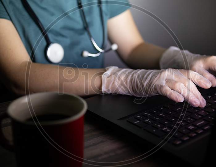 Doctor or nurse's hands on keyboard in the dark. Long hours or overtime work of medical worker concept.Doctor or nurse's hands on keyboard in the dark. Long hours or overtime work of medical worker concept.