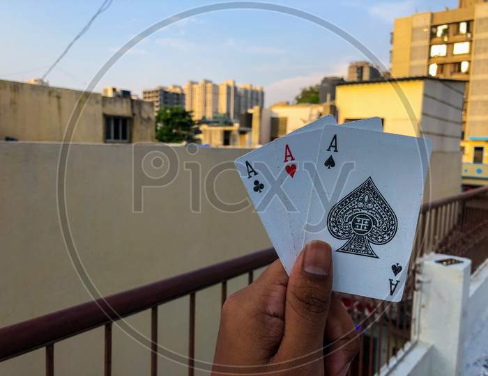 Young Indian Man Holding Poker or Playing Cards With Blur Background