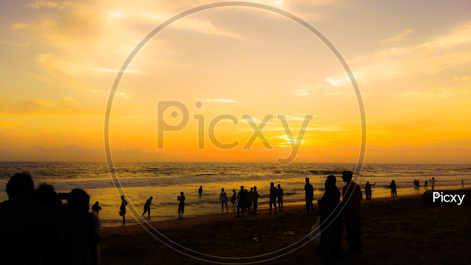 A Silhouette Landscape Image Of People Watching Sunset On A Beach In Kerala, India.