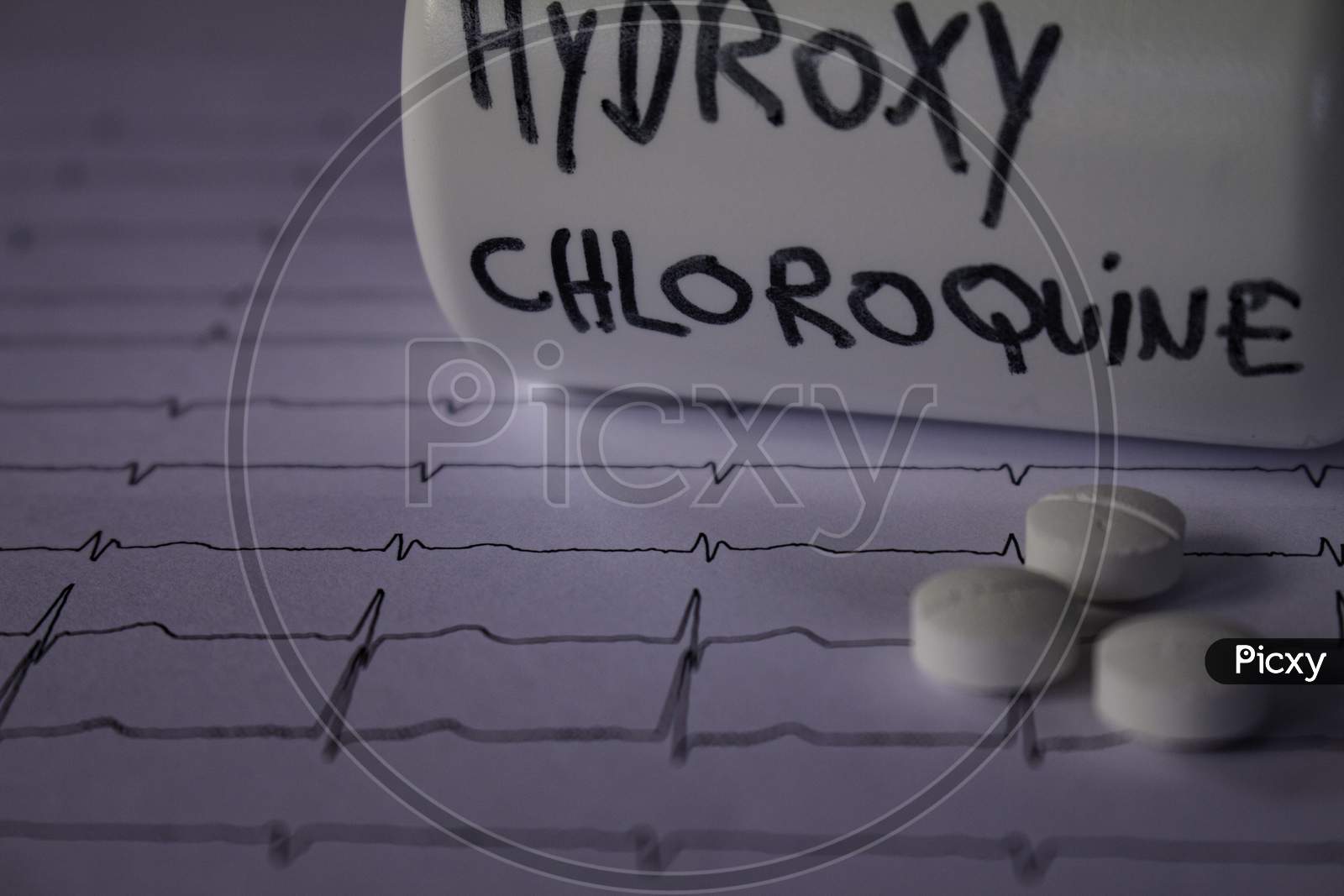 Adverse Effects On The Heart By Hydroxychloroquine Or Chloroquine. Pills On An Electrocardiogram. White Container With "Hydroxychloroquine" Written On The Side.