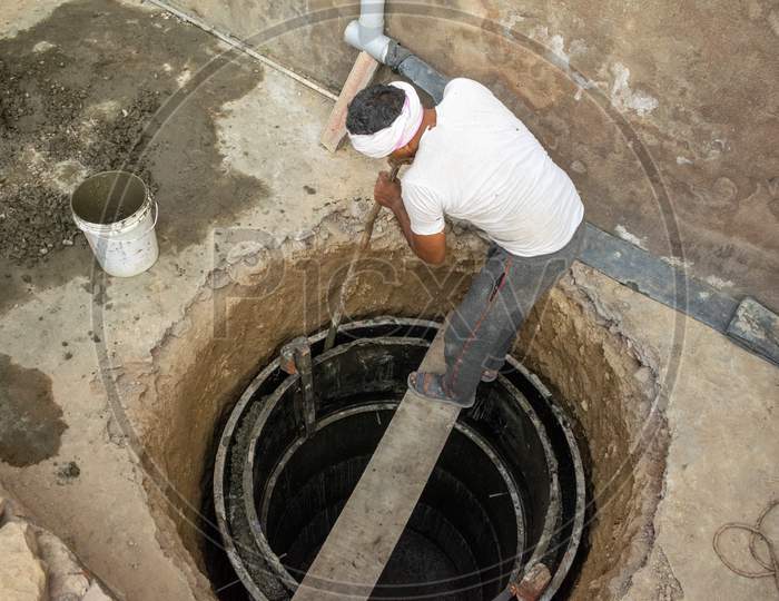 A man adjusts concrete in a mould during construction of a septic tank