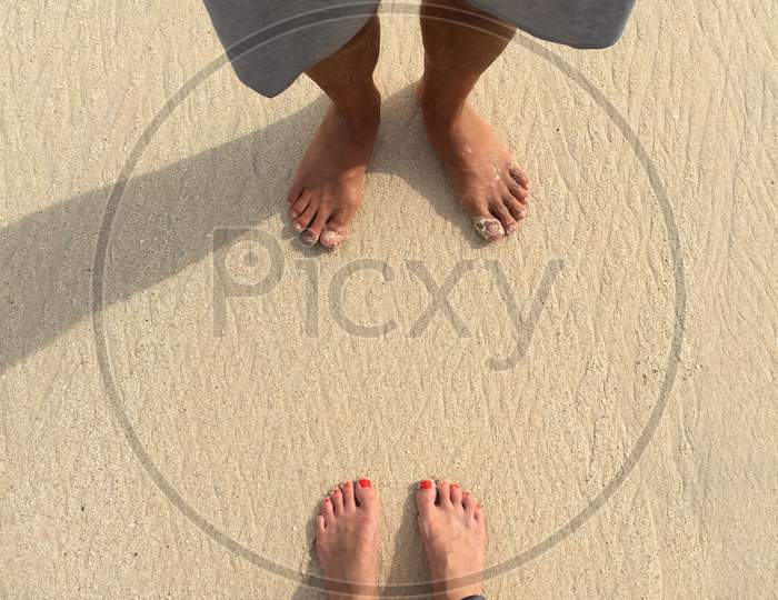 Male And Female Feet Standing On A Beach