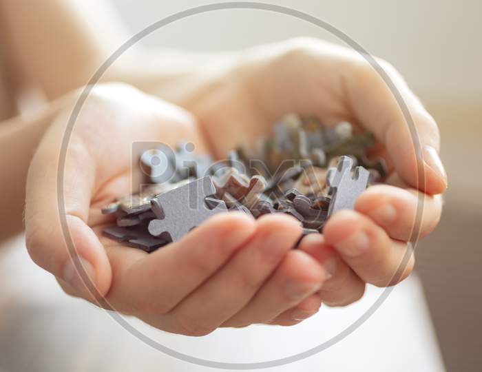 Mixed jigsaw puzzle pieces in hands, macro close up. Problem solving concept