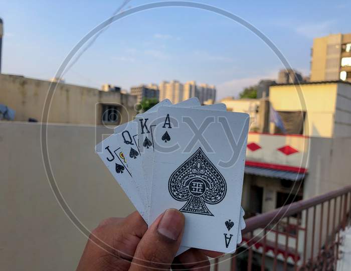 four cards in one hand with corporate buildings and blue sky in background