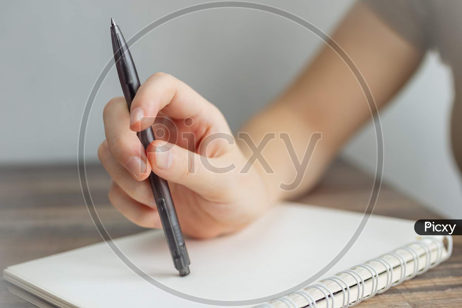 Vintage close up of female hand writing taking notes with pen in blank spiral notebook.