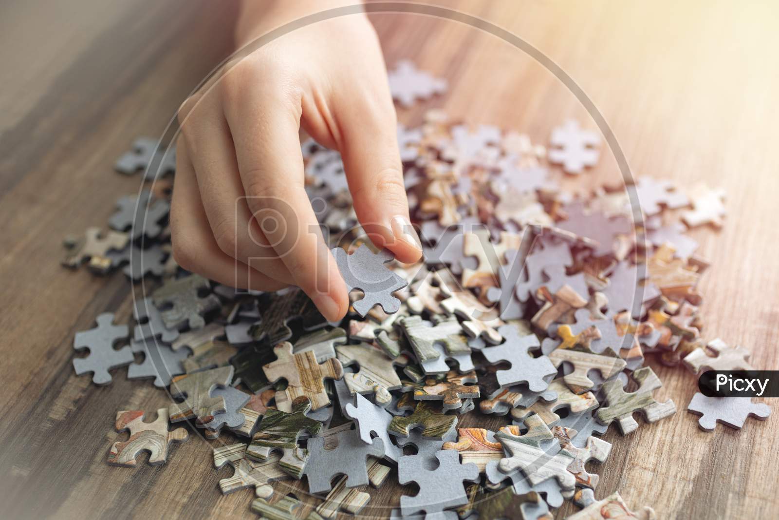 Hand picking one piece of mixed jigsaw puzzle, macro close up. Problem solving concept