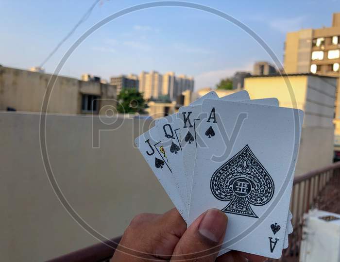 Asian guy holding four cards in hand with corporate background and blue sky