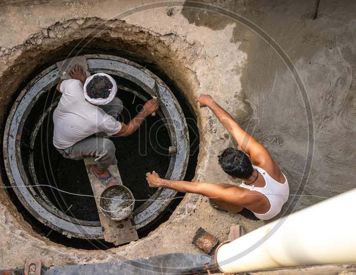 Men working during construction of septic tank outside a house